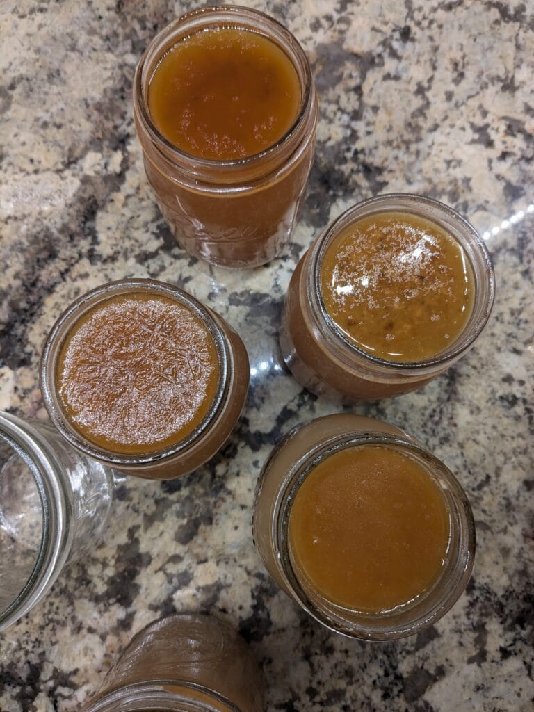 Many canning jars getting filled with broth.