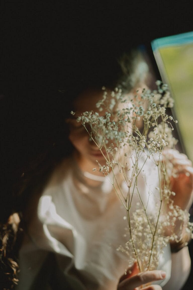 A blurred woman holding a stem on baby's breath to represent how someone feels after a miscarriage when they wanting another baby after loss