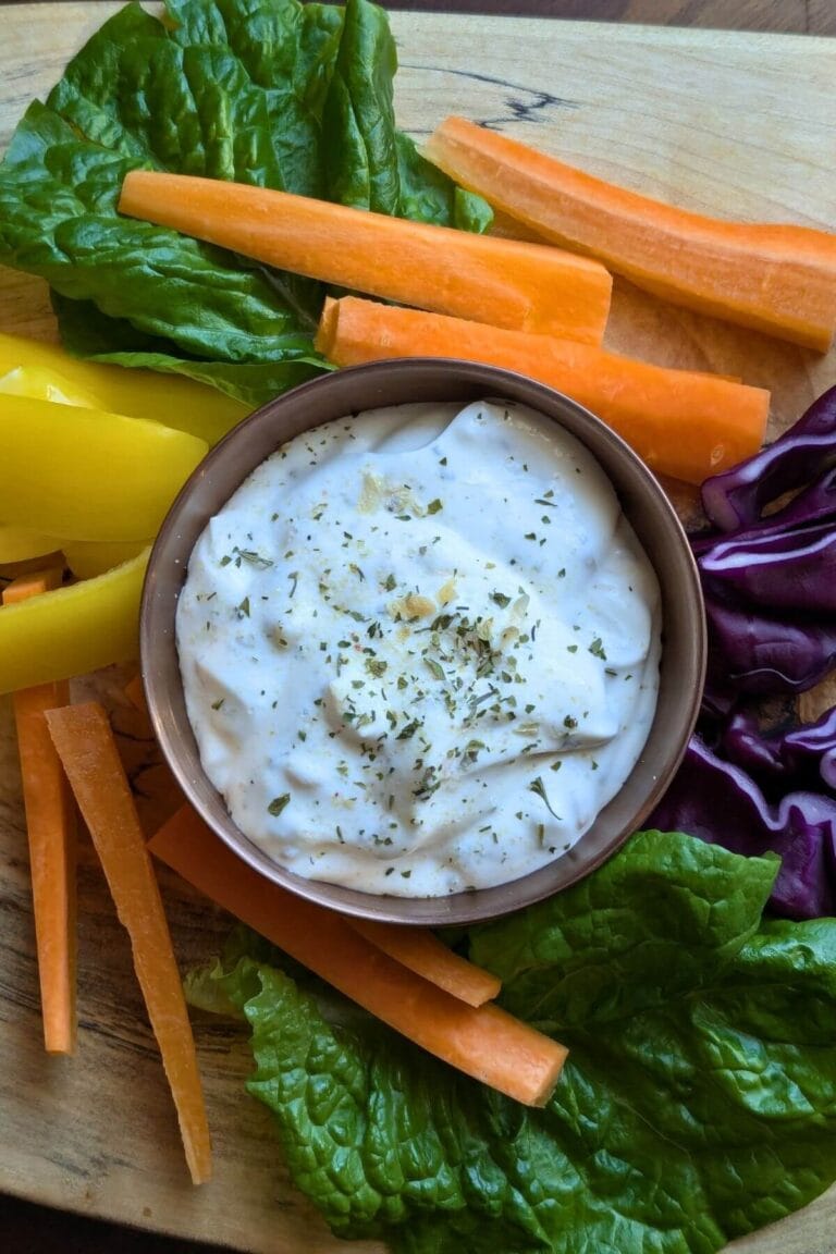 An array of vegetables arranged on a wooden cutting board to dip into homemade ranch dip made with dried herbs and spices and sour cream.