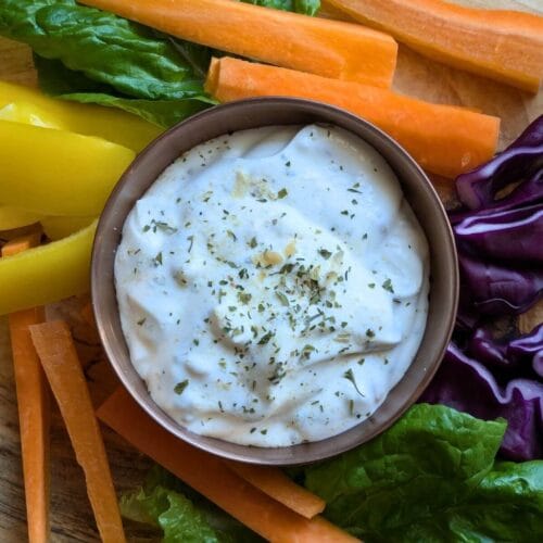 An array of vegetables arranged on a wooden cutting board to dip into homemade ranch dip made with dried herbs and spices and sour cream.