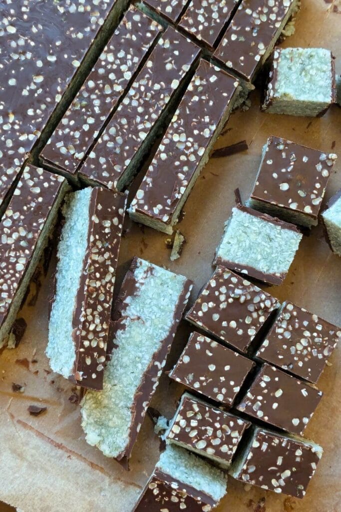 No bake dark chocolate coconut bars sliced into squares on parchment paper