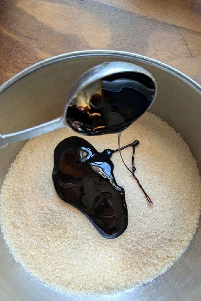 Granulated sugar and molasses being added to a mixing bowl.