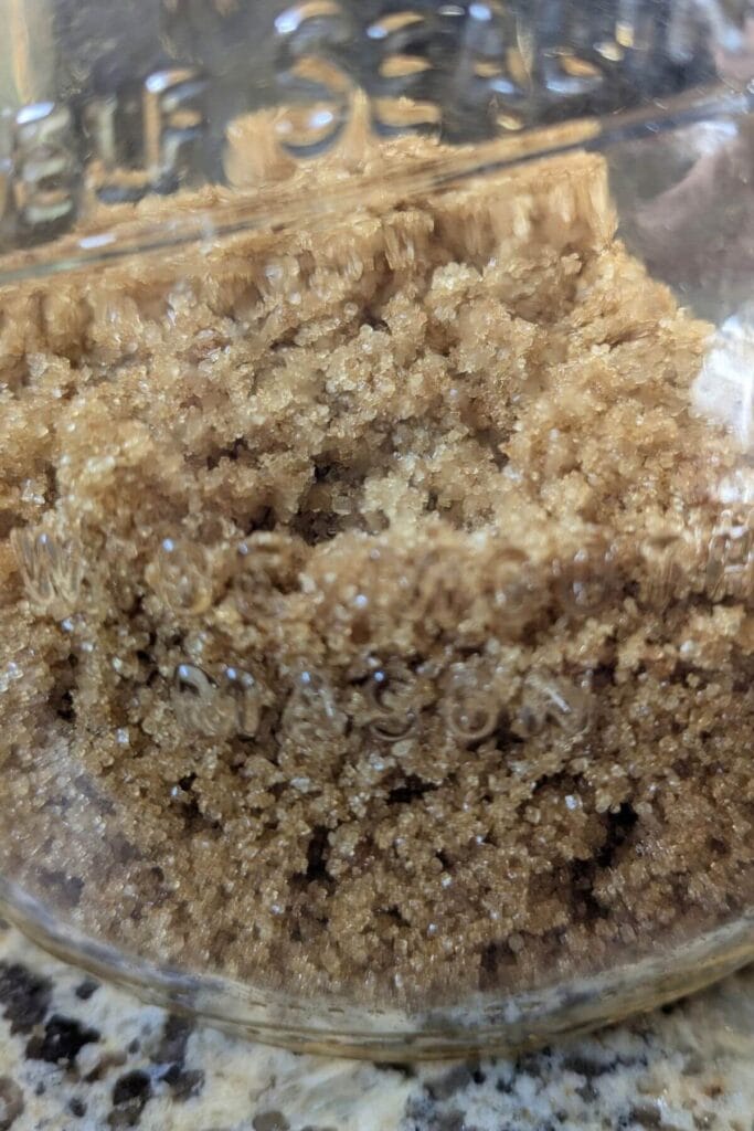 An airtight glass container of brown sugar, just mixed up from homemade with only 2 ingredients - white sugar and molasses.