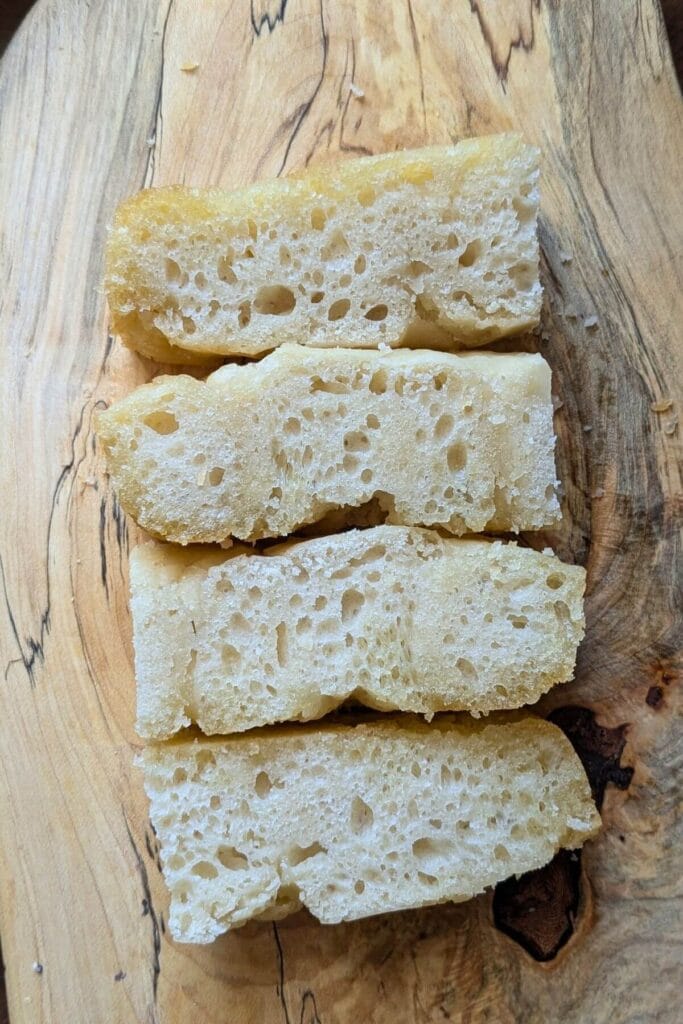 This is my same-day sourdough focaccia from cold fridge starter, sliced up on a cutting board to show how bubbly it gets!