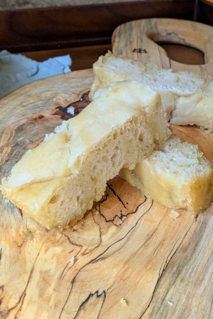 This easy sourdough focaccia starts with unfed starter straight from the fridge and can be baked the same day. Here are pieces sliced up on a cutting board for eating.