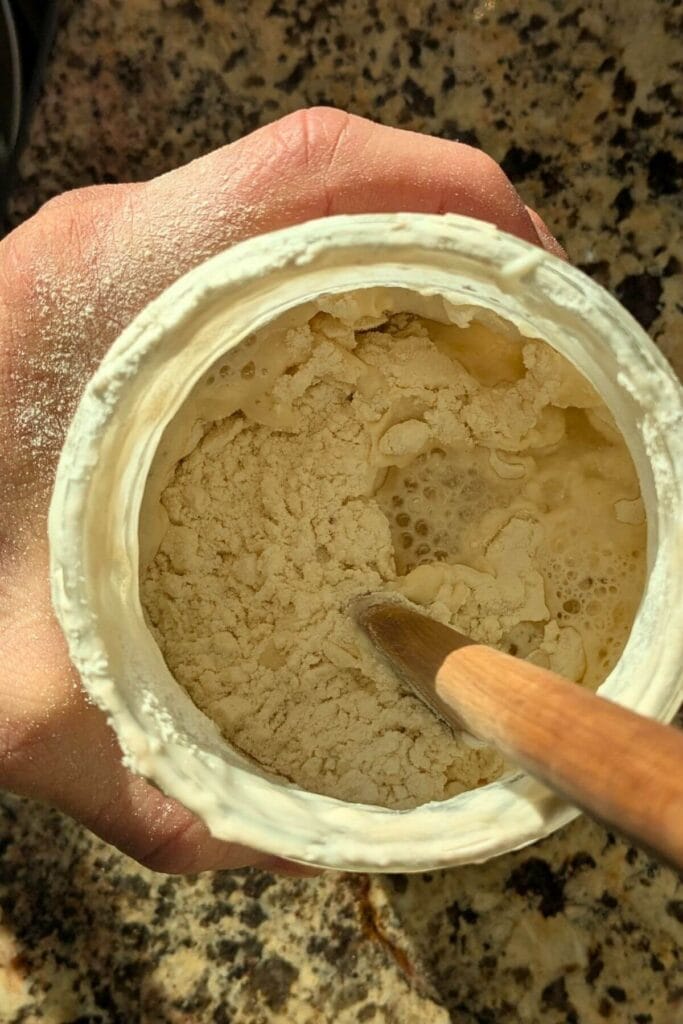 stirring a jar that has just been fed with fresh flour and water