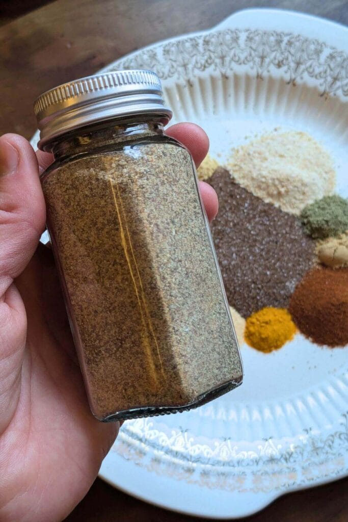 Ingredients for homemade chophouse seasoning including smoked salt, garlic, herbs and spices and finished seasoning in a glass jar