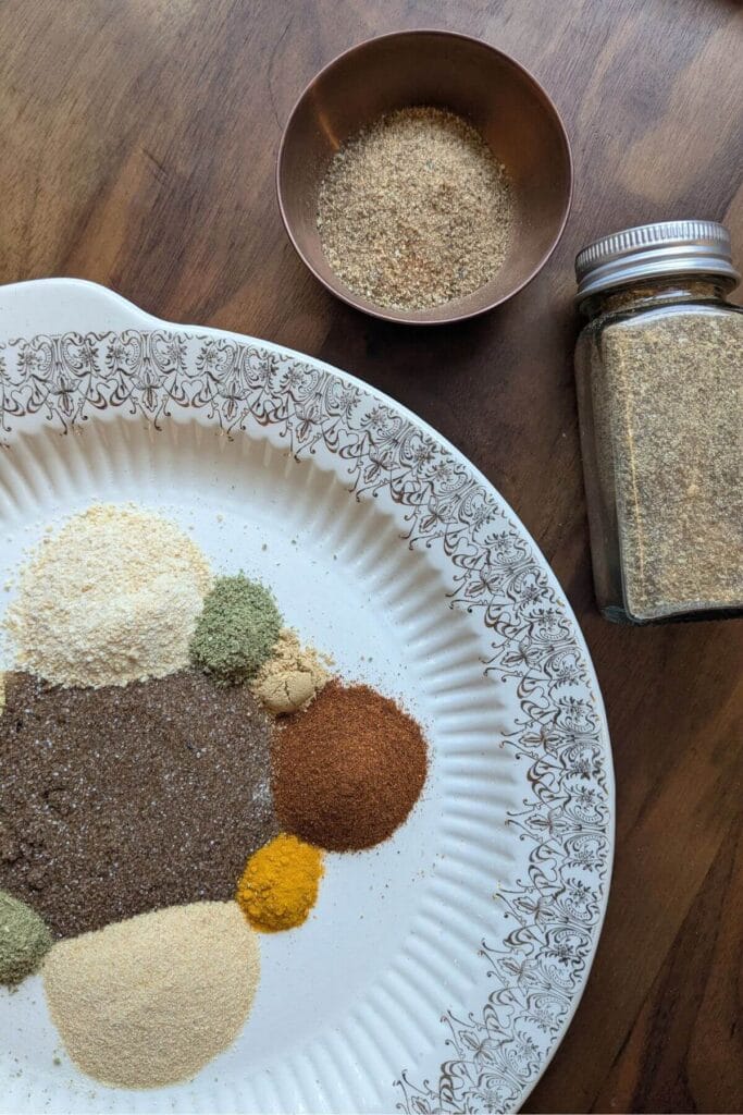Ingredients for homemade chophouse seasoning arranged with smoked salt, garlic, onion, herbs, paprika, ginger, turmeric, mustard and spices.