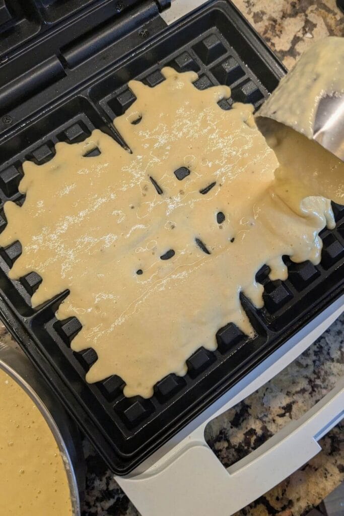 Thick sourdough waffle batter starting to cook in a waffle iron