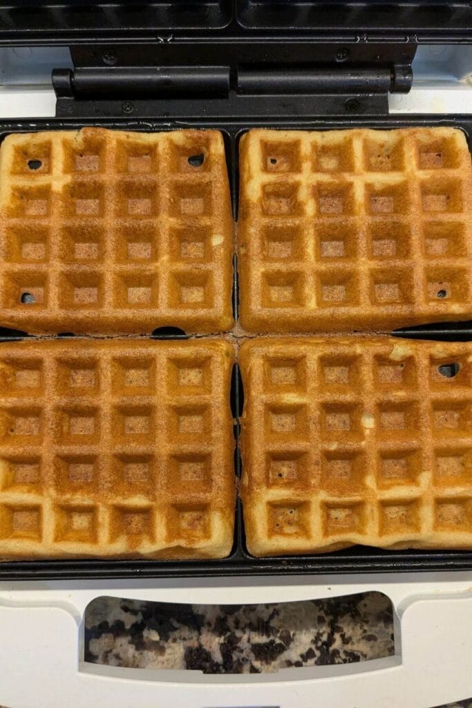 Sourdough waffle cooking in a hot waffle iron until golden and crisp